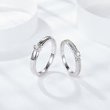 Top-down flat lay with rings arranged symmetrically beside a small gift box and ribbon