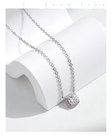 Hand holding square pendant necklace against neutral backdrop