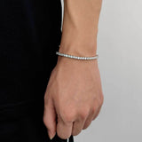 White gold plated cubic zirconia tennis chain bracelet worn on female wrist with black top against white background, iced out tennis bracelet for women everyday styling