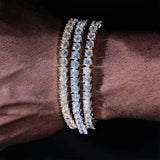 Three white gold plated cubic zirconia tennis chain bracelets stacked on a wrist, iced out bling stack for hip hop streetwear styling, layered tennis bracelet look