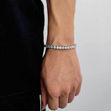 White gold plated cubic zirconia tennis chain bracelet modeled on female wrist with dark blue top, iced out bling bracelet for women, hip hop jewelry gift for her