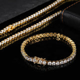 Three 18K gold plated cubic zirconia tennis chain bracelets stacked beside matching single round bracelet on black leather, iced out hip hop bling stack set for men and women