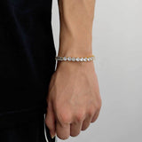 18K gold plated cubic zirconia tennis chain bracelet on female wrist with black clothing against white background, everyday iced out bling accessory for streetwear