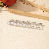 Sterling silver heart earrings worn on model's ear with soft-focus lifestyle background