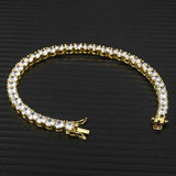 18K gold plated cubic zirconia tennis chain bracelet laid open on black ribbed surface, box clasp and tongue detail visible, iced out tennis bracelet product detail