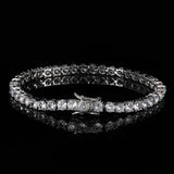White gold plated cubic zirconia tennis chain bracelet round hero shot on black reflective surface, single row of round cut CZ stones, iced out bling bracelet for men and women