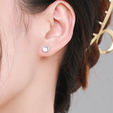 Lifestyle shot: moonstone stud earrings worn on ear against neutral fabric backdrop