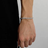 White gold plated cubic zirconia tennis chain bracelet on female wrist with black clothing, hip hop iced out bling accessory for everyday streetwear styling
