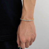 18K gold plated cubic zirconia tennis chain bracelet on female wrist with black clothing, iced out bling bracelet for casual streetwear and everyday wear
