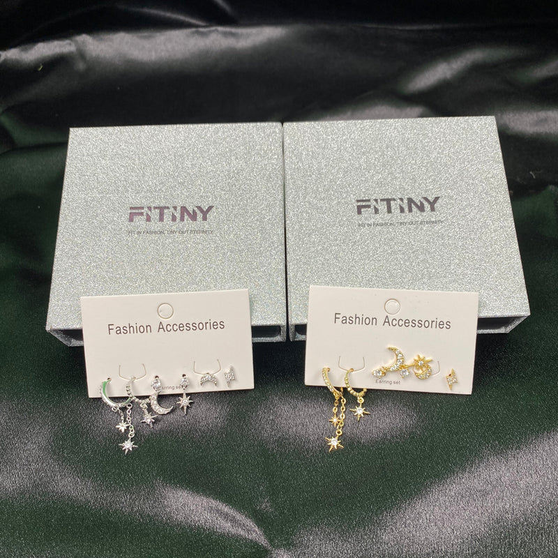 Star-shaped earrings on display with FITINY branded cards and boxes on a dark fabric background.