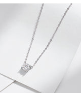 Woman laughing while adjusting round pendant necklace