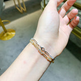 Bracelet layered with two thin chains on wrist, demonstrating stacking versatility
