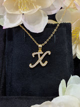 X letter pendant on marble surface for elegant, high-end visual context