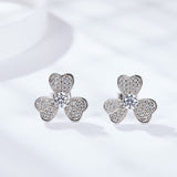 Lifestyle image of clover stud earrings worn on earlobe against soft natural lighting