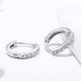 Side profile showing smooth circular shape and stone setting detail of silver hoop earrings