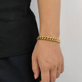 Gold 10mm Cuban link bracelet draped on wrist with natural lighting