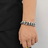 Steel 18mm Cuban link bracelet worn with layered chains for bold contrast