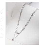 Lifestyle image of necklace worn at the collarbone with simple white turtleneck