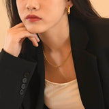 Necklace worn layered with thinner chain for styling reference