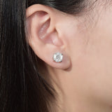 Lifestyle shot of earrings worn on earlobe against neutral linen backdrop