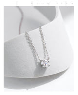 Flat lay with necklace, care cloth, and brand tag on light gray surface