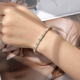 FITINY geometric cross bracelet in white gold and gold tones on white background