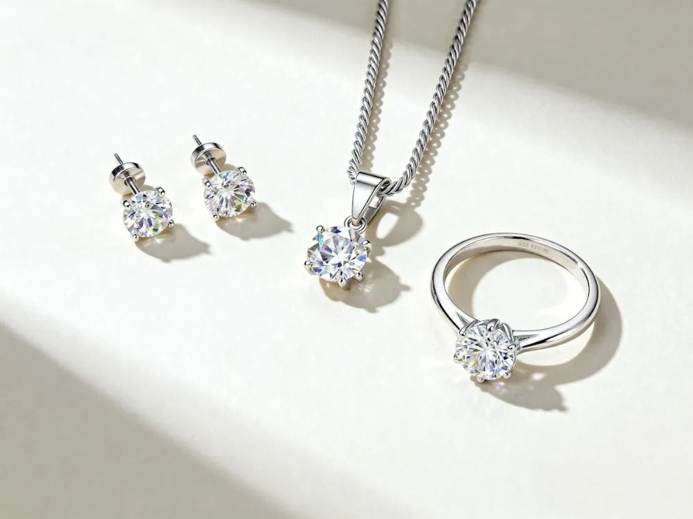 Classic moissanite studs, pendant and ring in rhodium-finished 925 silver on a light background.