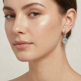 Moissanite halo drop earring worn on a woman's ear — dainty 6.5mm stone close-up