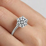Woman wearing a six-prong round moissanite engagement ring